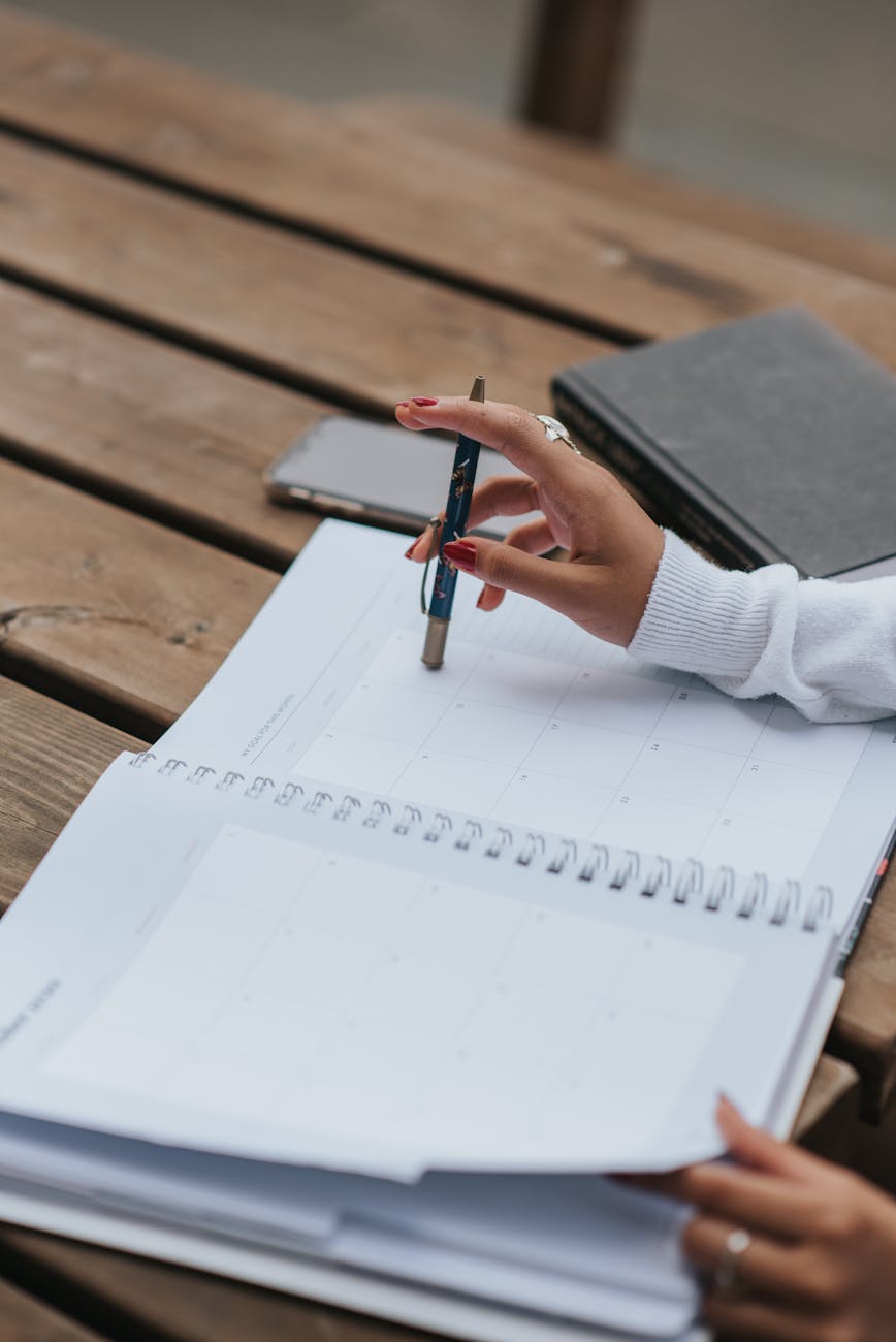 crop ethnic businesswoman with open notepad at table